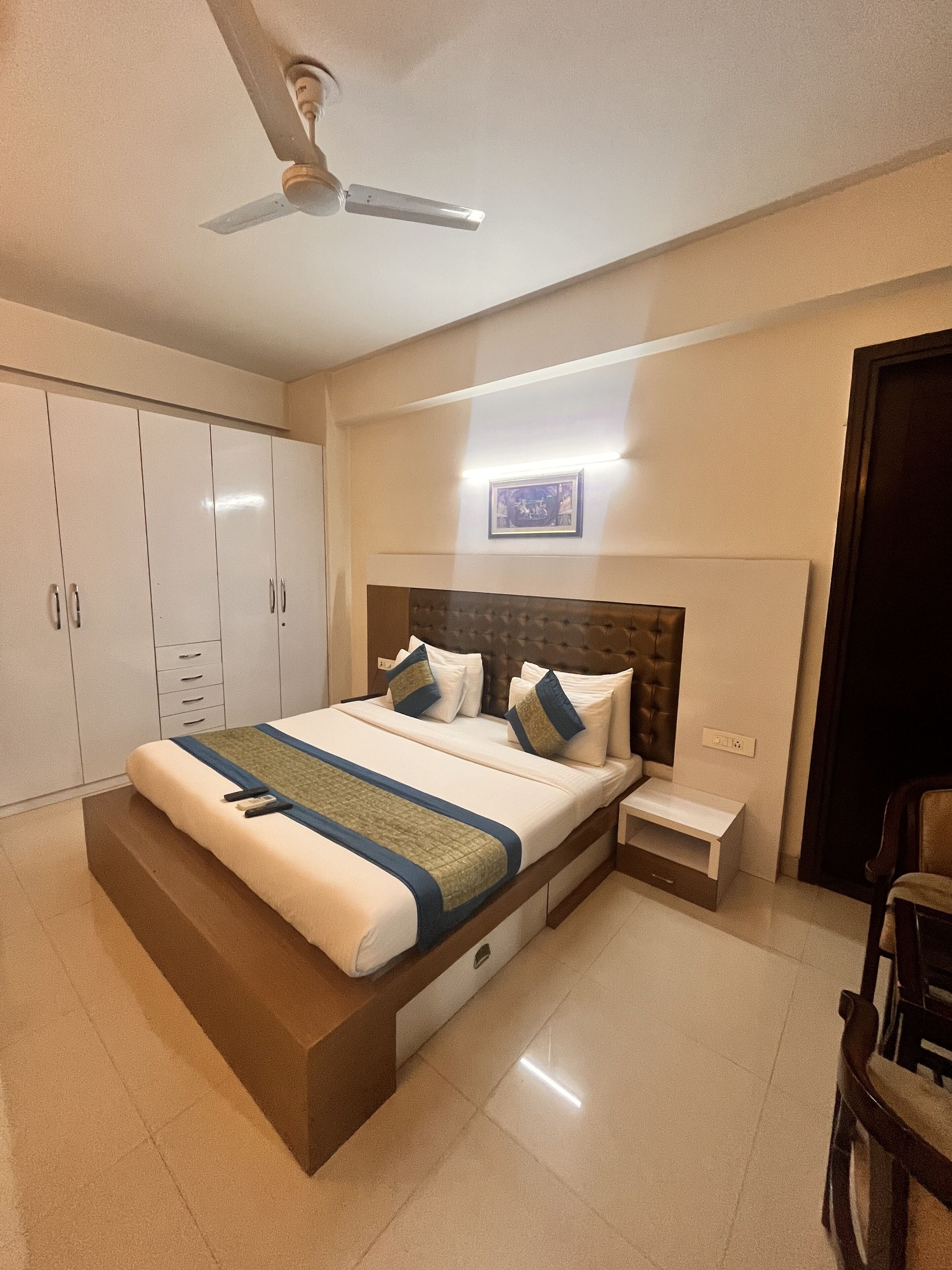 A bedroom with a bed, nightstands, a wardrobe, and a ceiling fan.