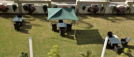 A patio area with a green canopy, outdoor seating, and small plants.