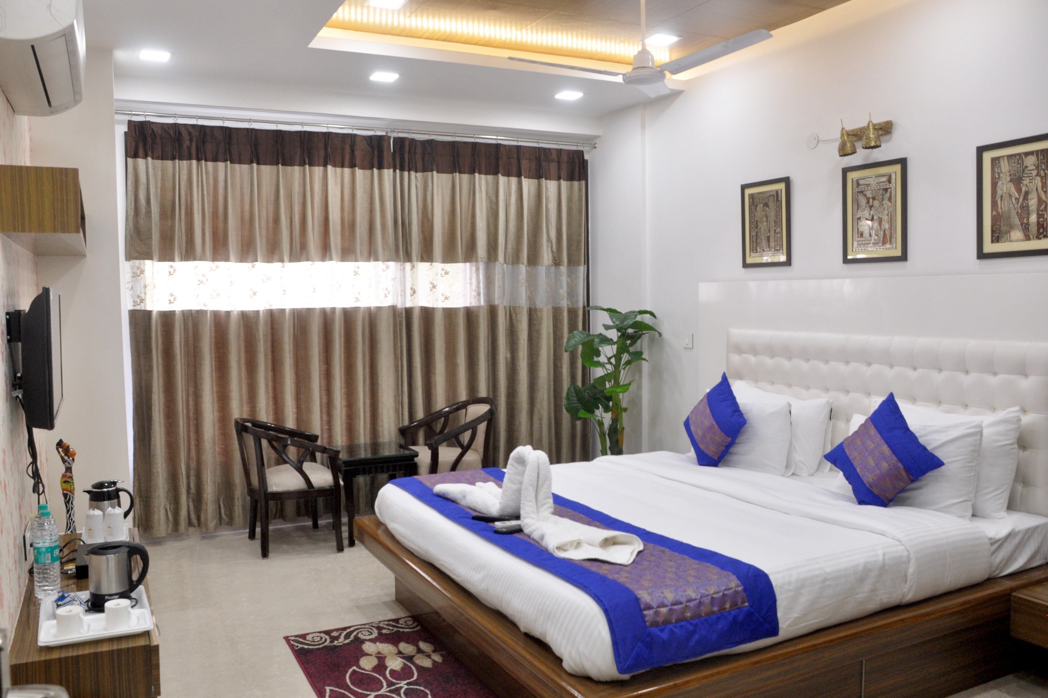 A hotel room with a large bed, a desk with a chair, a TV, and a window with curtains.
