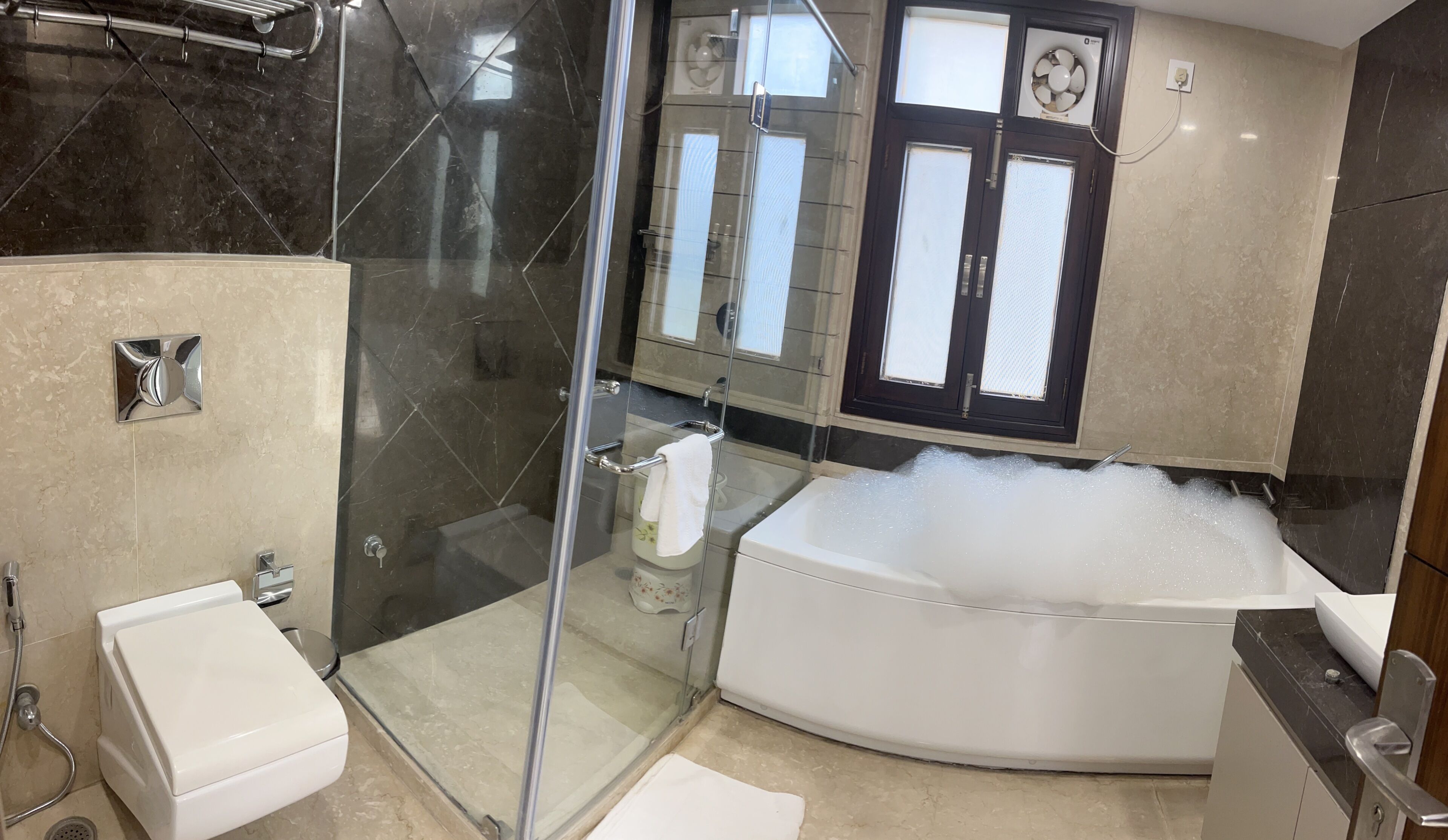 Un baño moderno con ducha de vidrio, una bañera independiente y un inodoro con toallero.