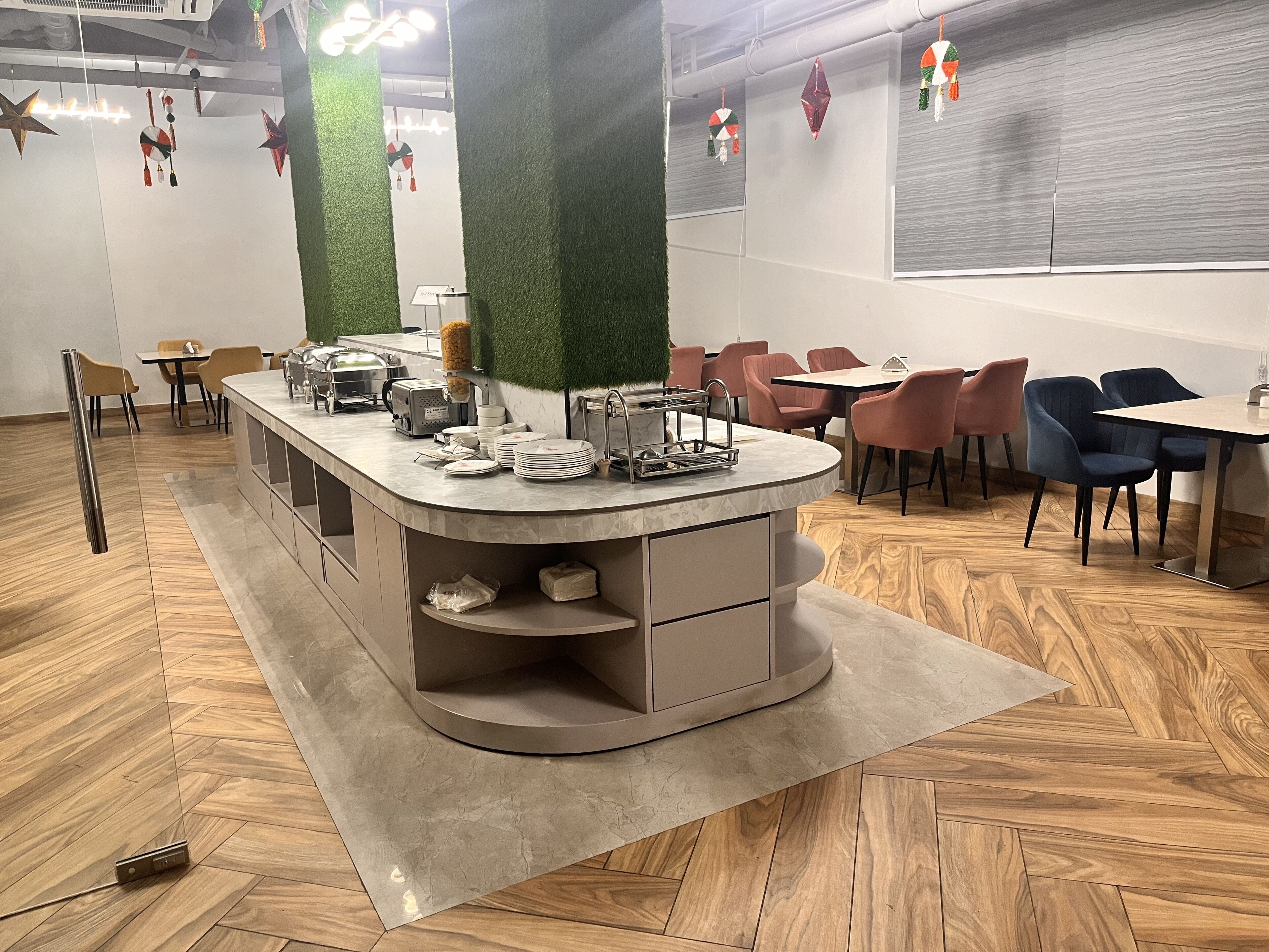 Un área de comedor moderna con una isla central, diversas opciones de asiento y adornos decorativos en la pared.