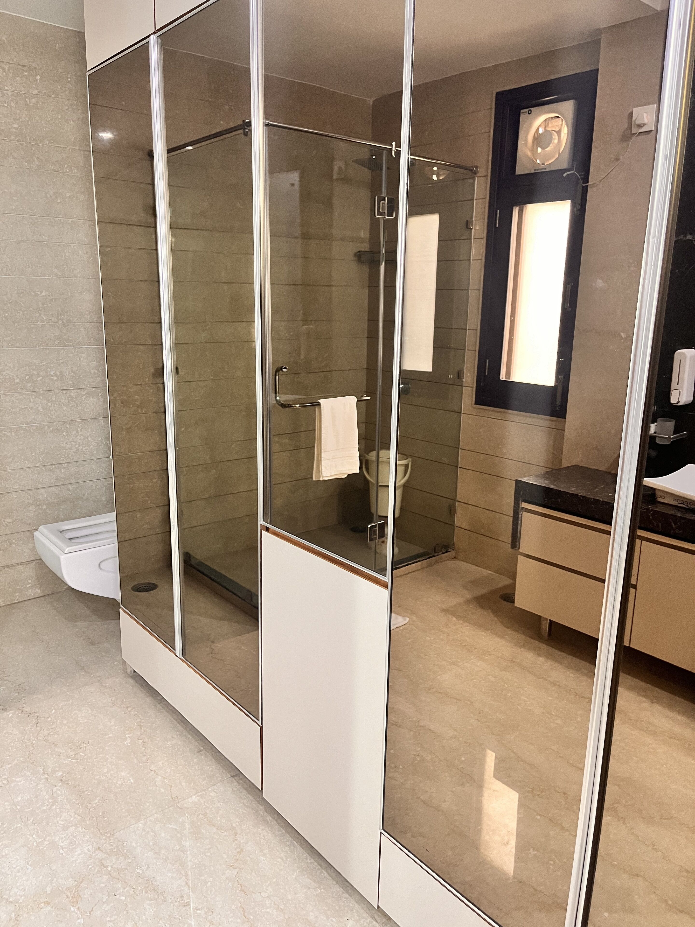 A modern bathroom with a glass-enclosed shower, a vanity with a mirror, and a toilet.