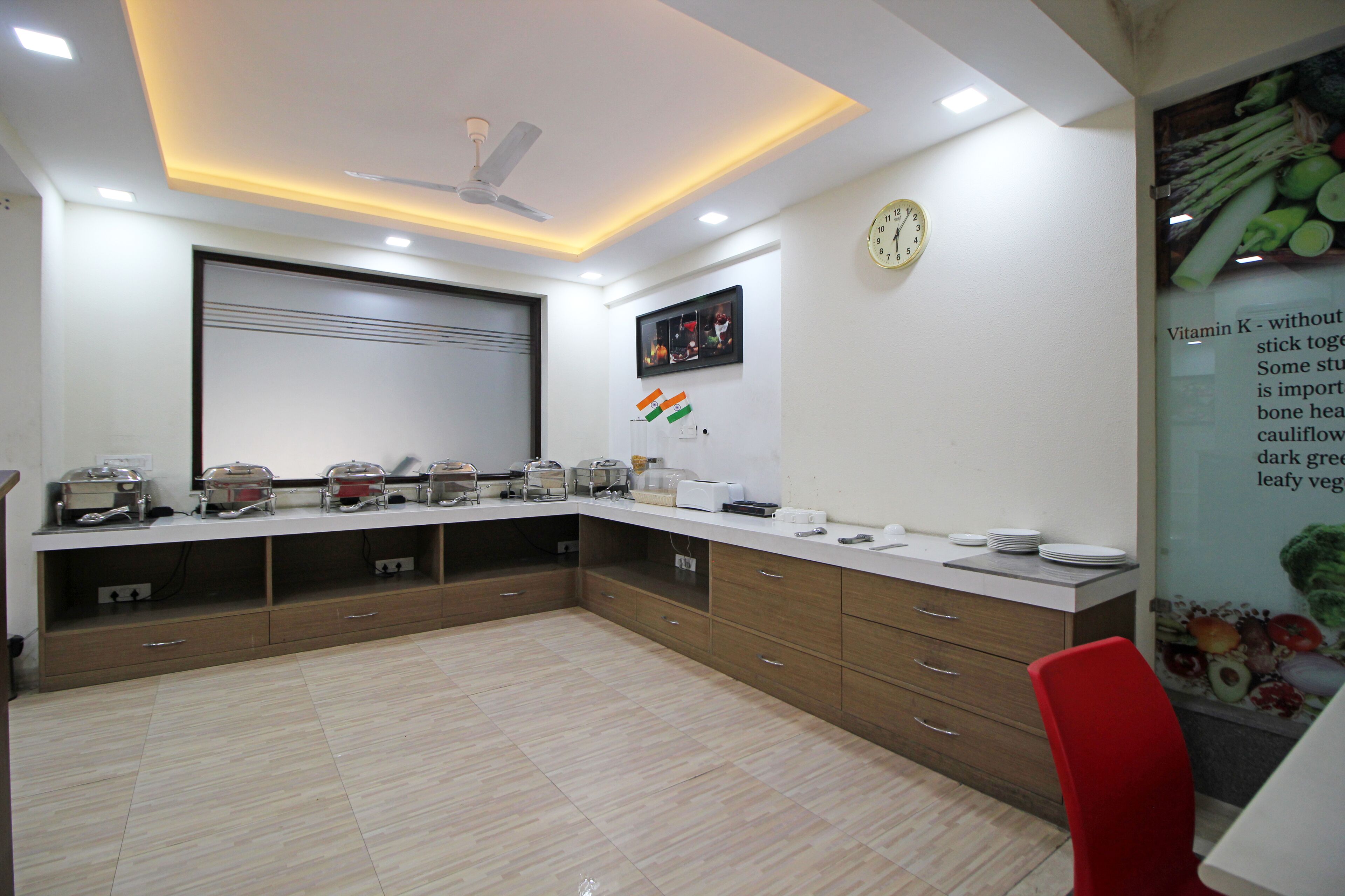A modern kitchen with a white countertop, wooden cabinets, and a red chair.