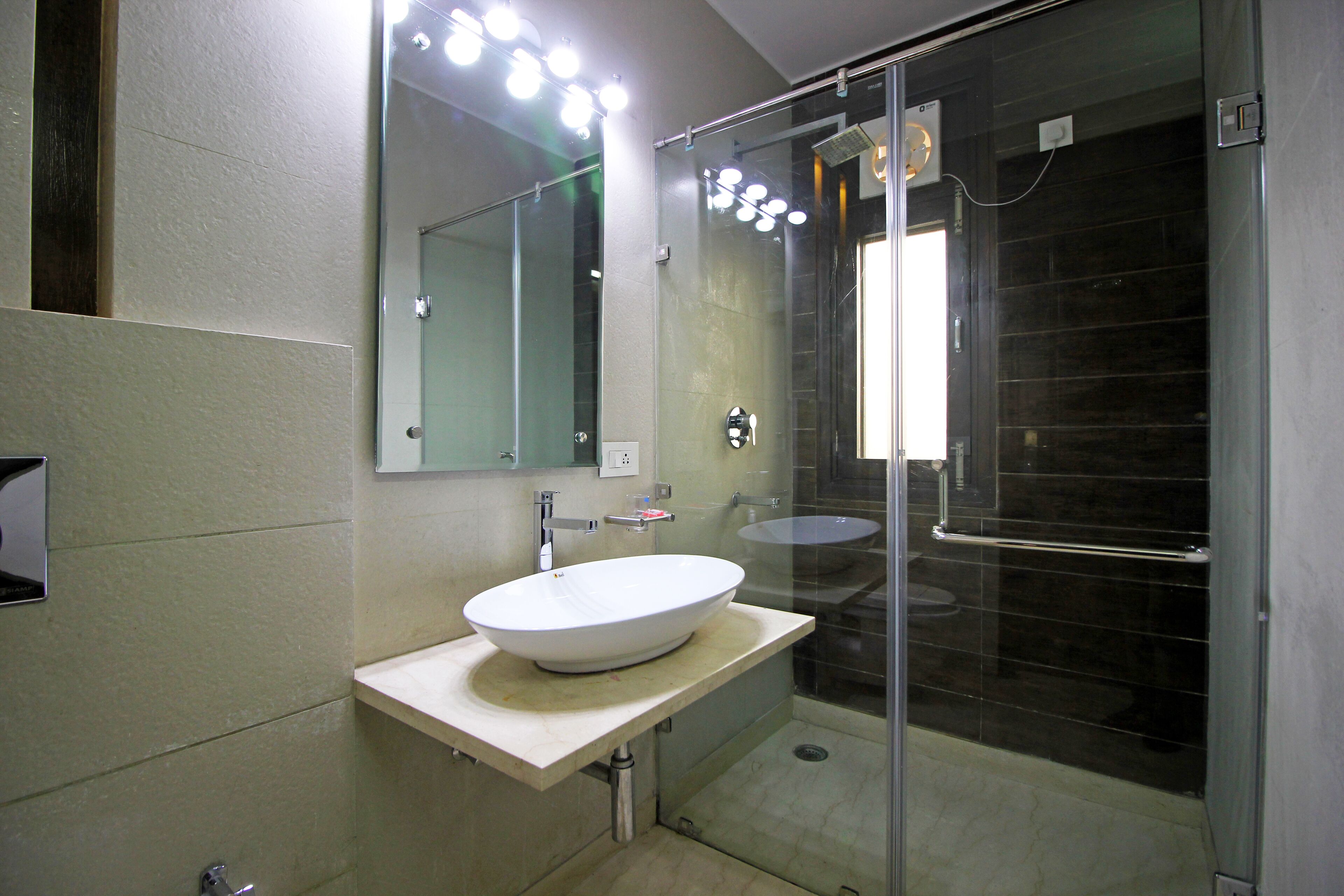 A modern bathroom with a large mirror, a white sink, and a glass shower enclosure.