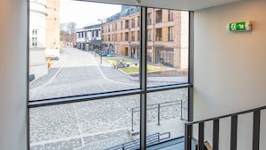 A modern interior with large windows, a staircase, and a view of the street outside. - City Lights Apartments (Kraków)