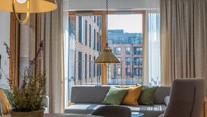 A modern living room with a sofa, a chair, and a hanging lamp. - City Lights Apartments (Kraków)