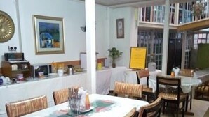 Comedor con una larga mesa dispuesta para una comida, rodeada de sillas de madera con asientos acolchados.