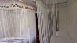 Una habitación con una cama cubierta por una mosquitera, una mesita de noche y una silla.