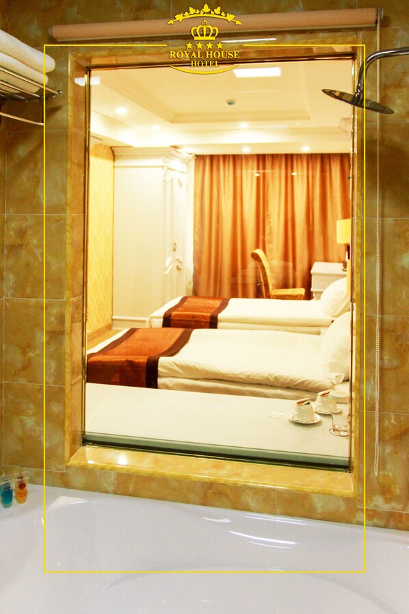 A hotel room with a large mirror, two beds, a shower, and a bathroom with a bathtub.
