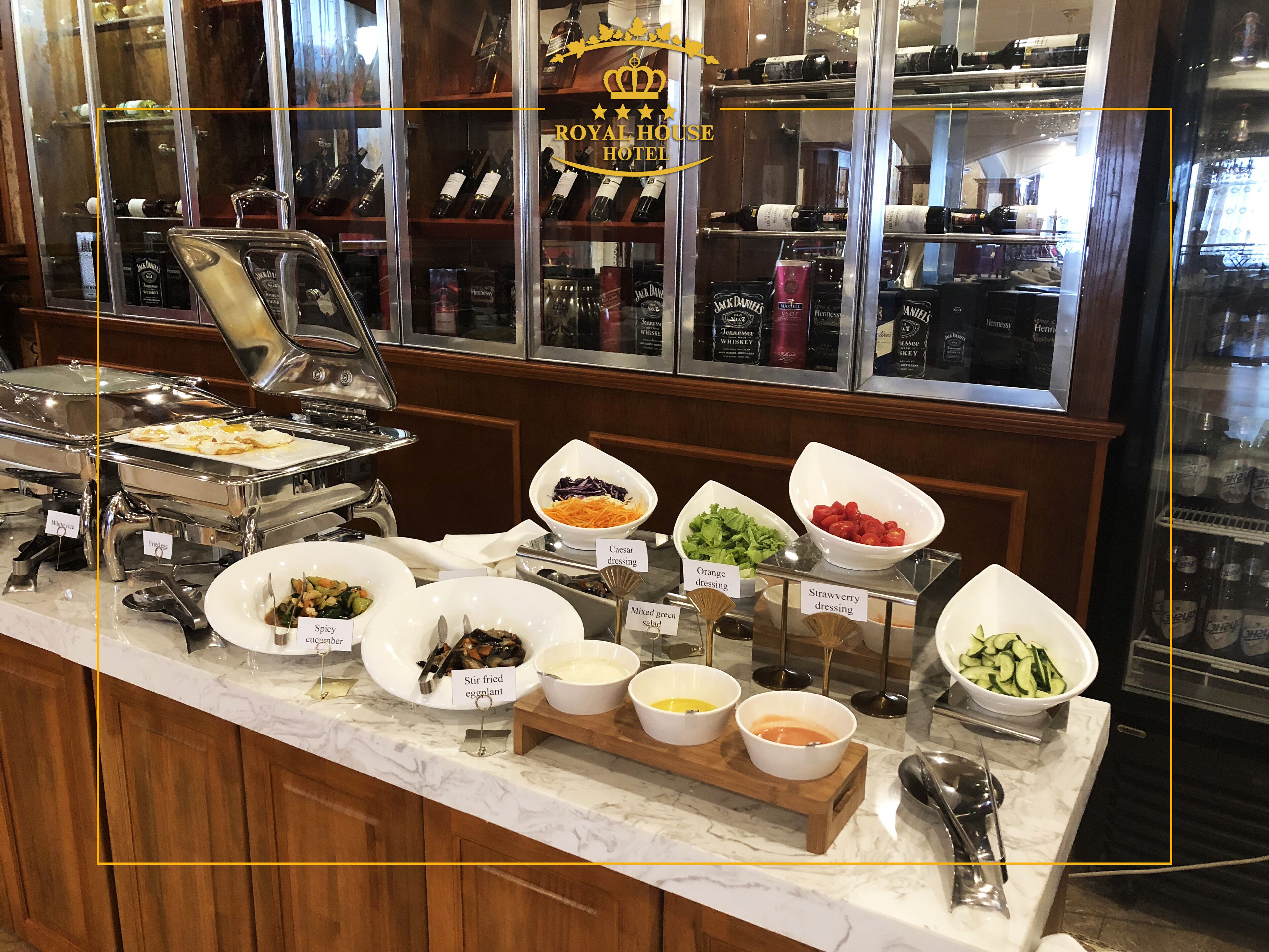 Mostrador de buffet con diversas opciones de comida y una selección de bebidas alcohólicas.
