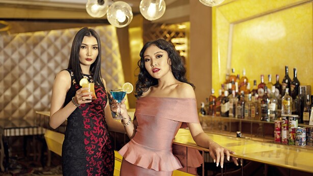 Two women in a bar setting with a variety of liquor bottles in the background. - Royal House Hotel 2 (Ulaanbaatar)