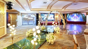 A grand hall with a stage, floral decorations, and a large screen. - Royal House Hotel 2 (Ulaanbaatar)