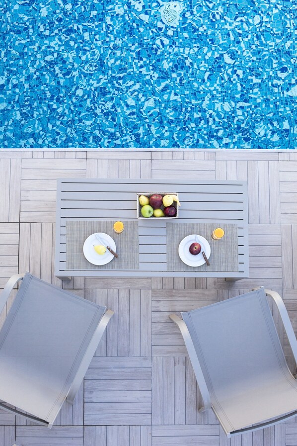 An outdoor dining area with a pool in the background.