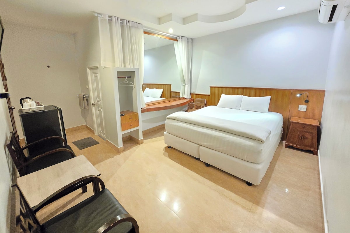 Ein Hotelzimmer mit Bett, Schreibtisch, Stuhl, Kleiderschrank und Nachttisch.