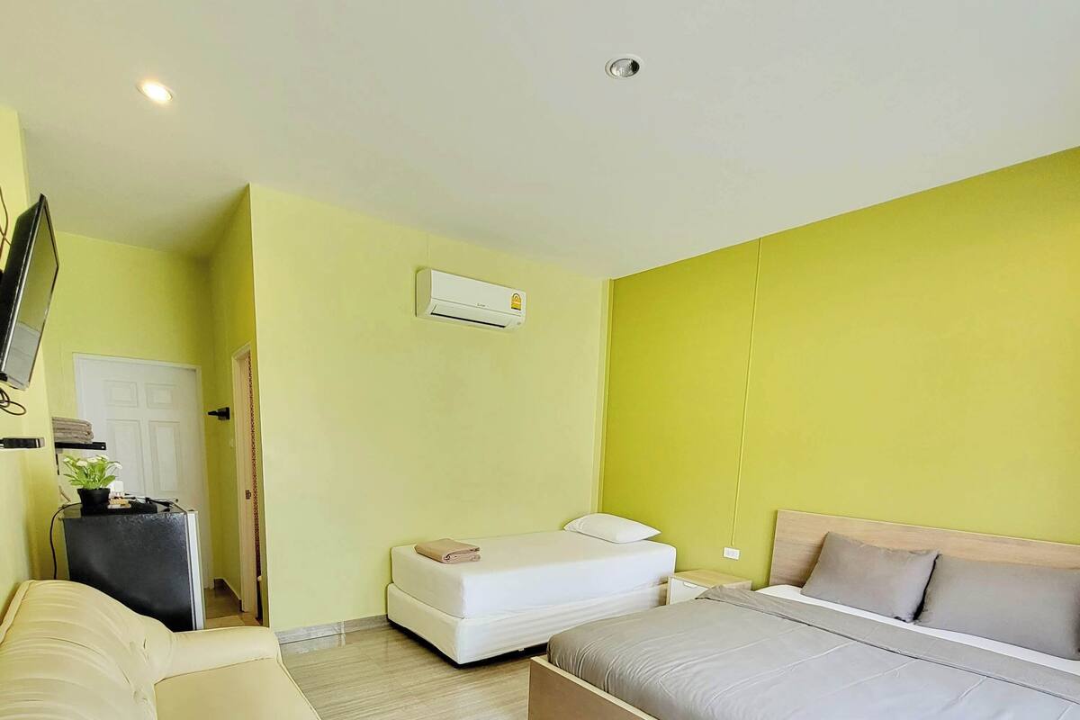 Ein modernes Schlafzimmer mit Bett, einer Couch und einem Fernseher.