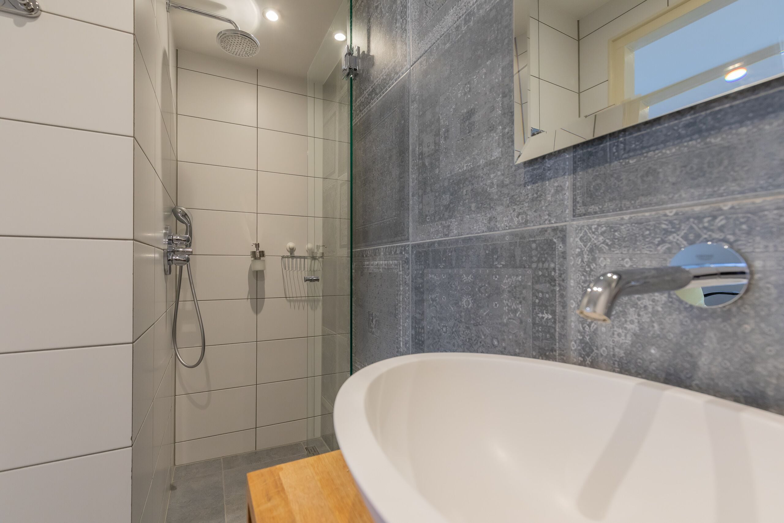 Une salle de bain moderne avec une douche à parois de verre, un lavabo blanc et un miroir.