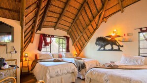 Een kamer met twee bedden, een televisie, een lamp en een decoratieve leeuw aan de muur.