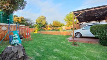 Enjoy a spacious backyard with a lawn, water source, shaded area, and parking.