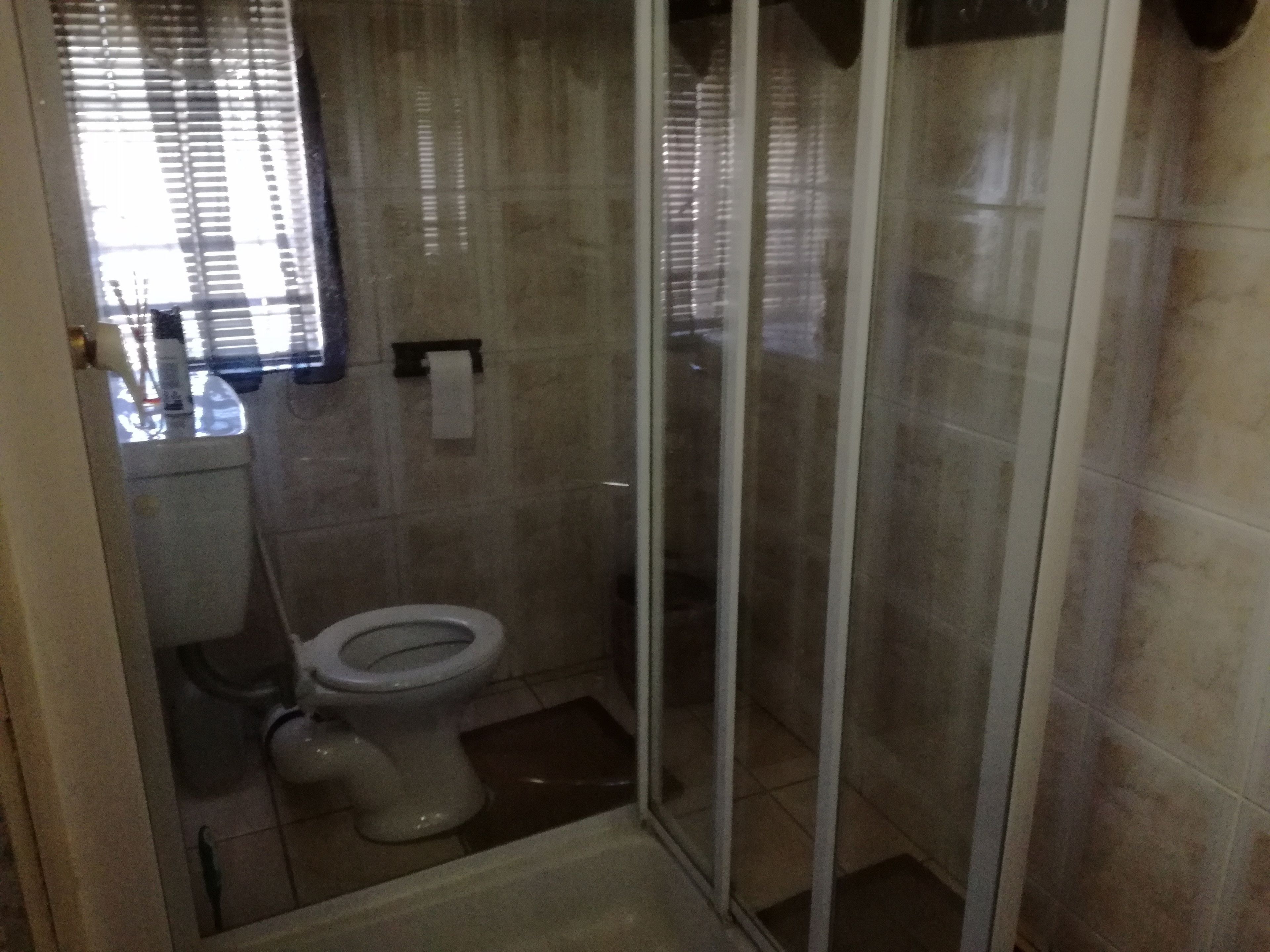 A bathroom with a toilet, a glass shower enclosure, and a towel rack.