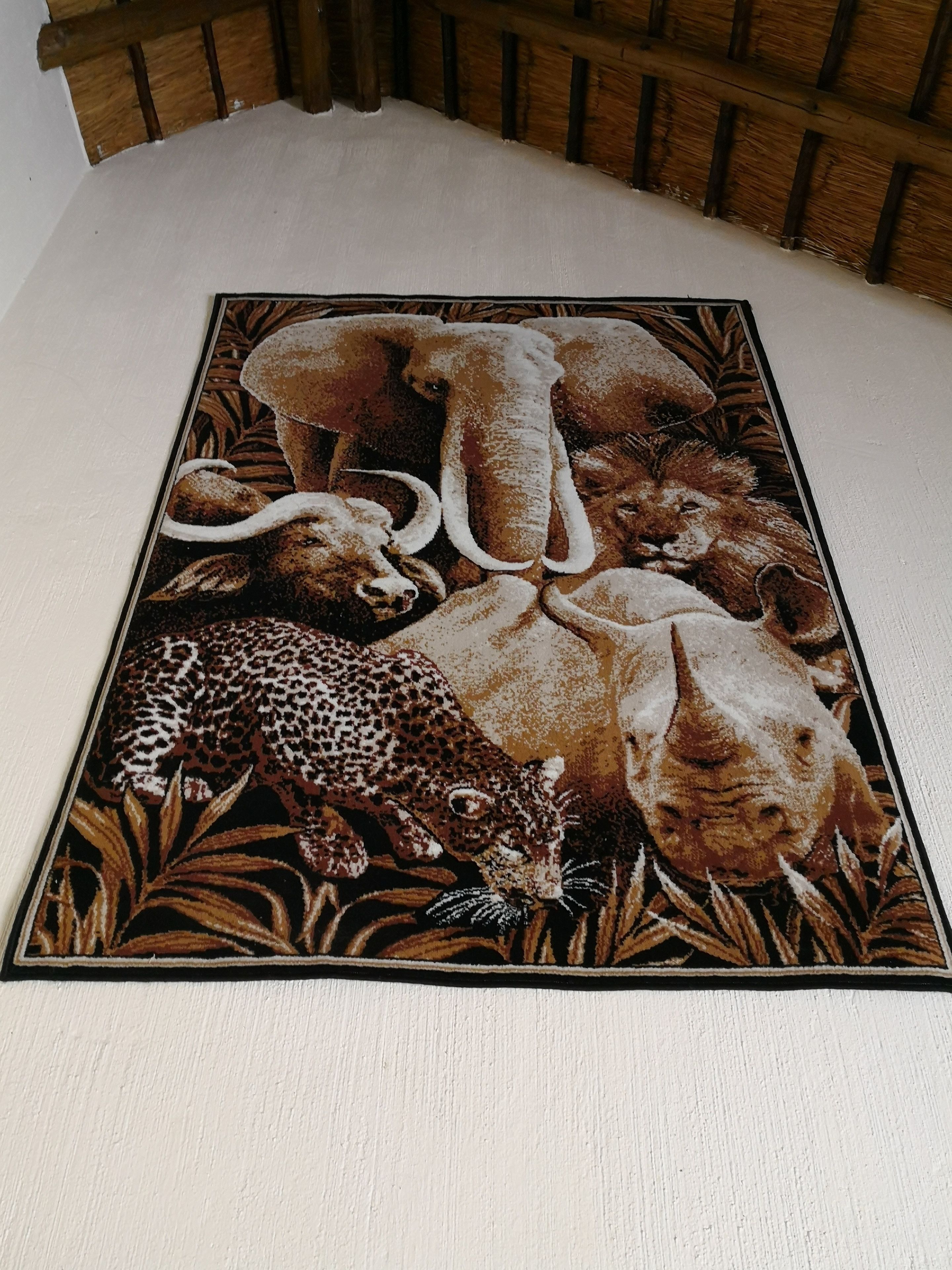 Une tapisserie richement détaillée, sur le thème de la faune, représentant des éléphants, des rhinocéros et un léopard.