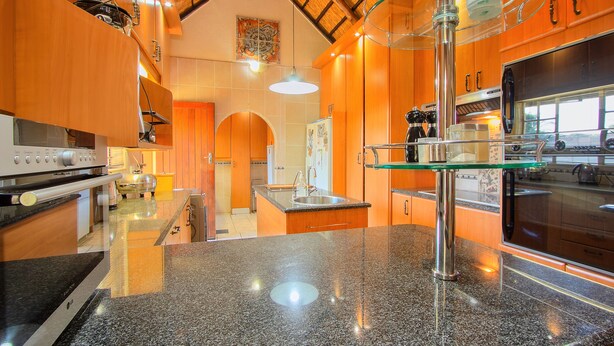 Een moderne keuken met granieten aanrecht, roestvrijstalen apparatuur en houten kastjes.
