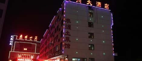 Un hotel con señalización iluminada, varios pisos y una entrada visible.