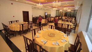 Un comedor con mesas redondas dispuestas para el servicio, candelabros y vistas al exterior.