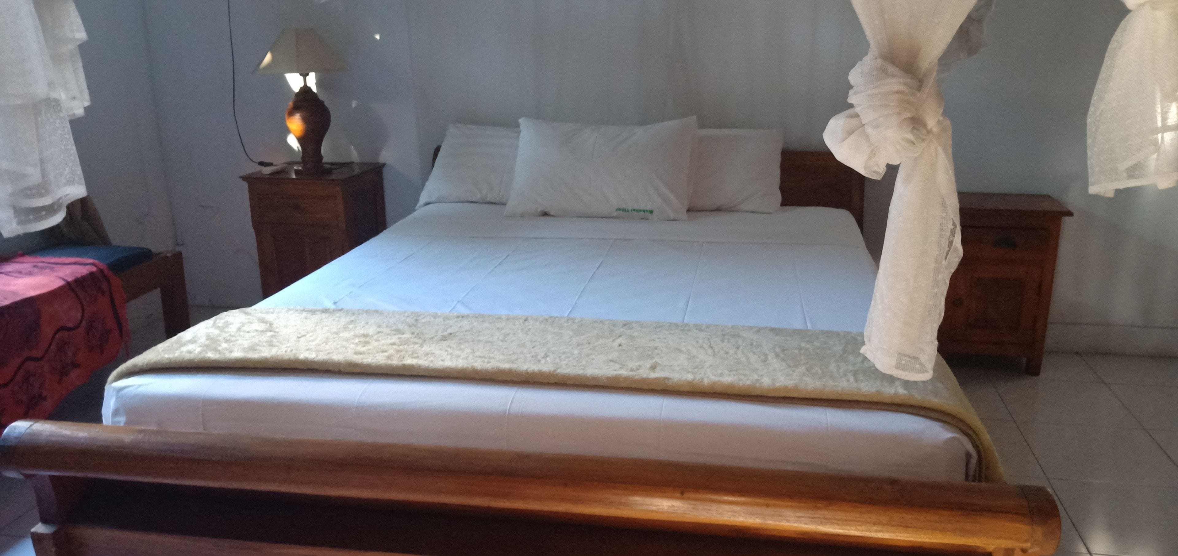 Un dormitorio con cama, mesita de noche con lámpara y cabecero de madera.