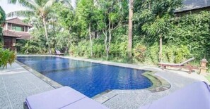 A swimming pool surrounded by lush greenery and a small building with a tiled roof. - Villa Mahalini 1 Seminyak (Seminyak)