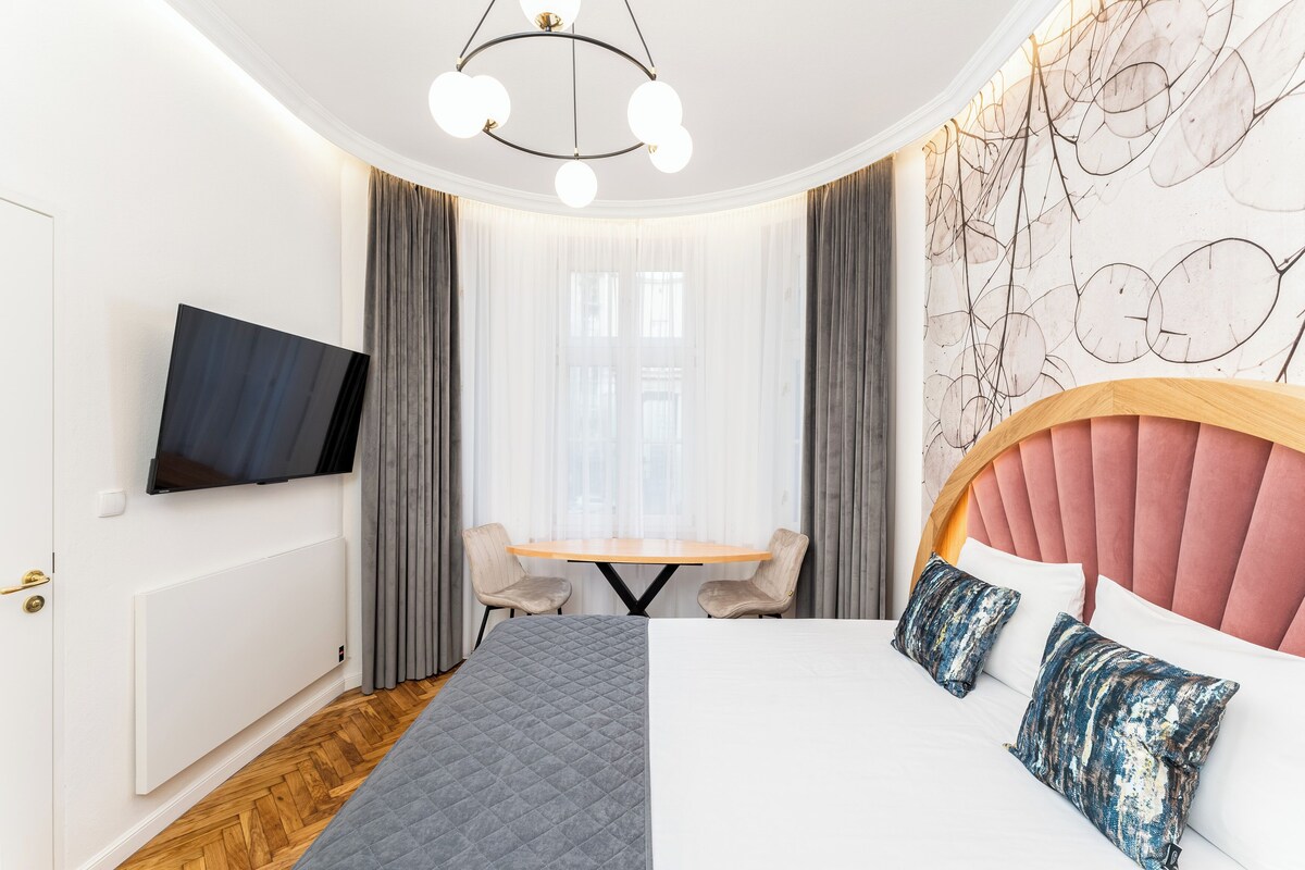 Et hotelværelse med seng, fjernsyn, spisebord og stol.