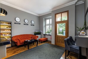 En moderne stue med en rød sofa, en sort lænestol og en trædør.