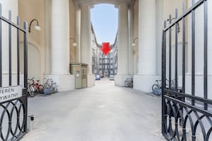 En korridor med søjler, et rødt pileskilt og cykler parkeret langs siderne.