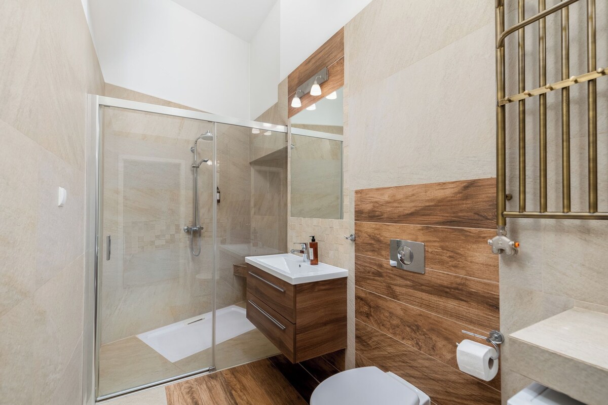 Une salle de bain moderne avec une douche à parois de verre, un meuble-lavabo en bois et des toilettes.