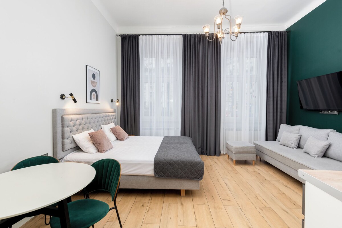 Et moderne soveværelse med seng, sofa, fjernsyn og spiseplads.