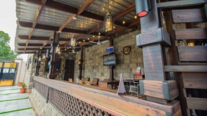 A bar area with a stone wall, wooden beams, and hanging lights. - NAP APARTMENT HOTEL (Accra)