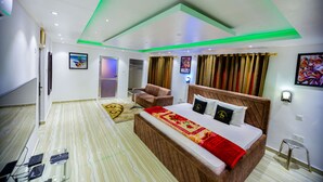 A modern hotel room with a large bed, a desk, a chair, and a bathroom. - NAP APARTMENT HOTEL (Accra)