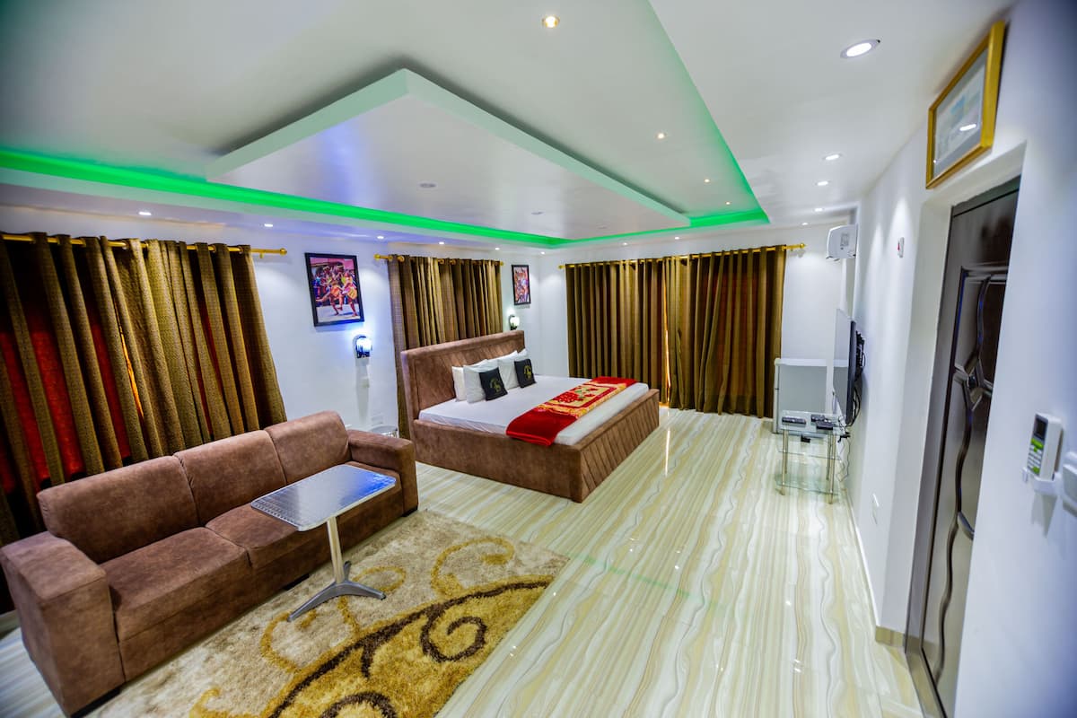 A hotel room with a bed, a sofa, a small table, and a television.