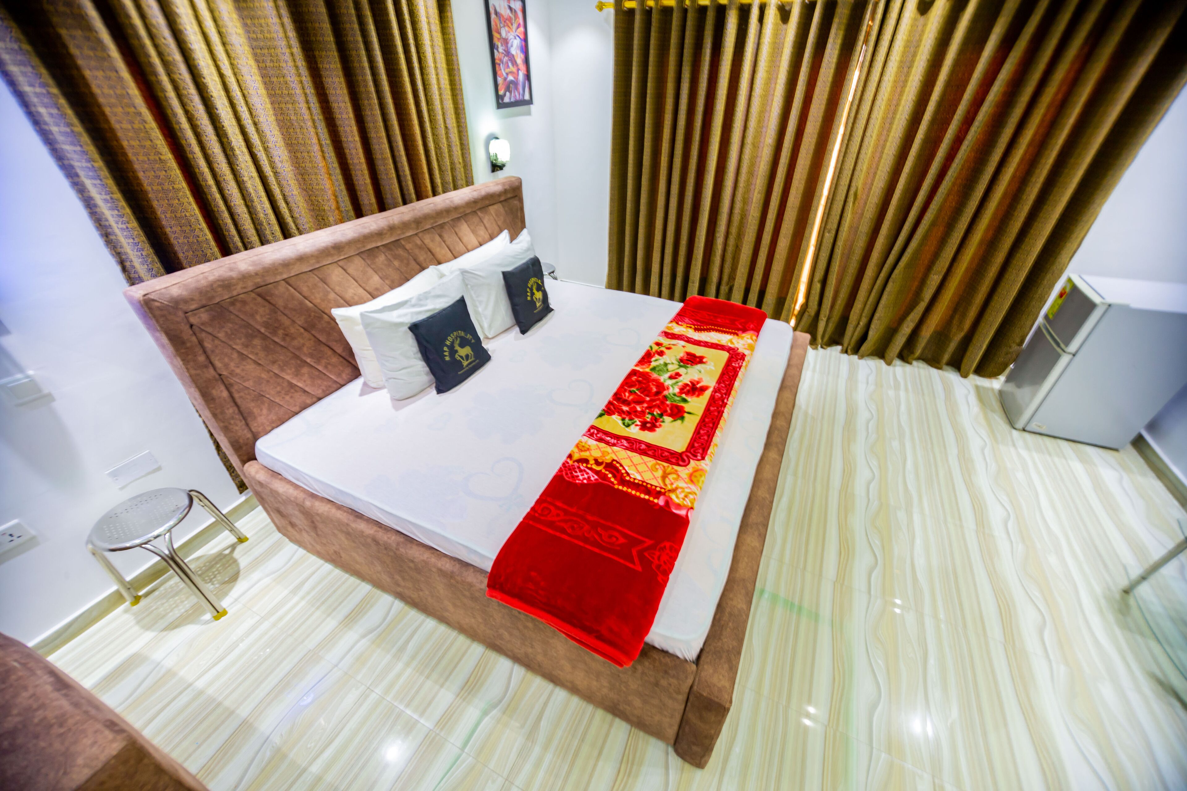 A neatly made bed with a red blanket, a wooden headboard, and two pillows.