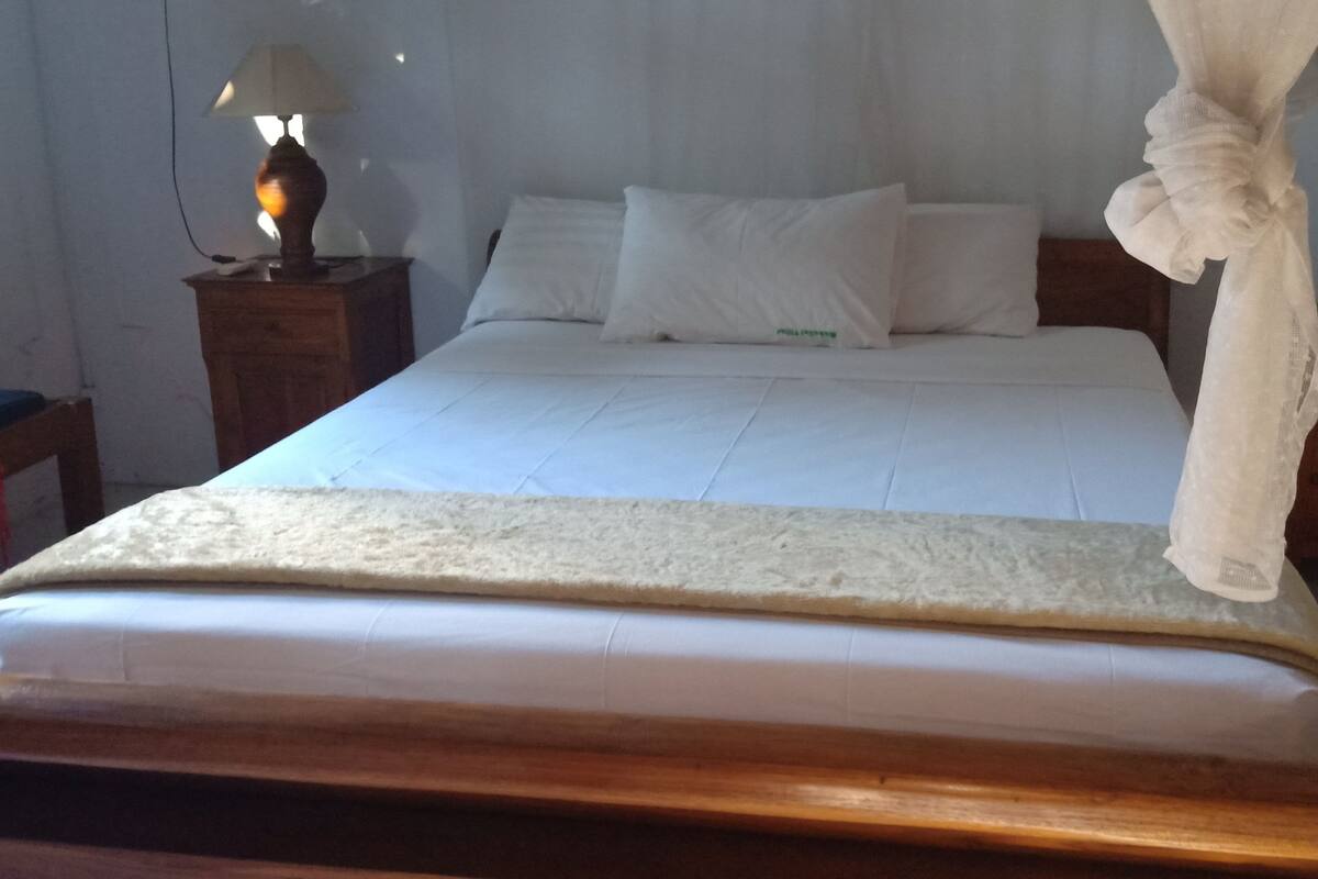 A bedroom with a bed, a nightstand with a lamp, and a wooden headboard.