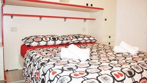 A bedroom with a bed, red headboard, and a patterned bedspread. - Mario Apartment 3028 F (Venice)