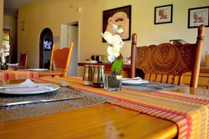 Una mesa de comedor lista con platos, cubiertos y una pequeña orquídea en maceta.