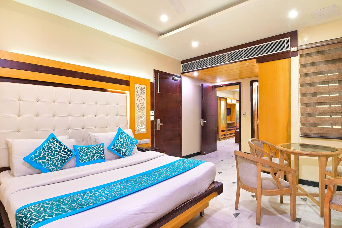 A hotel room with a large bed, a wooden headboard, a bedside table, and a chair.