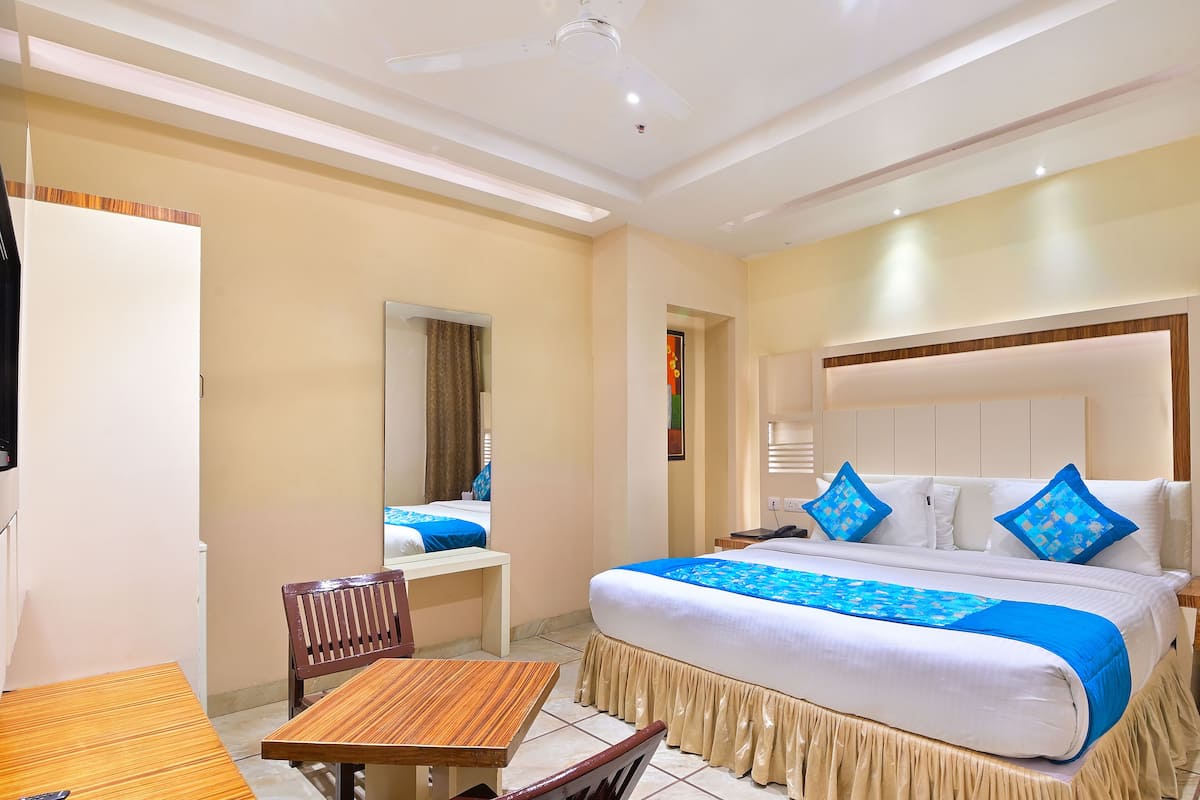 A hotel room with a large bed, a wooden table, and a chair.