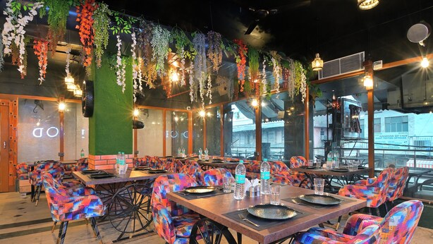 A restaurant with colorful patterned chairs, tables set with plates, glasses, and water bottles. - Hari Piorko Inn Express (New Delhi)