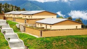 Una hilera de edificios tradicionales con un camino de piedra que los lleva hacia arriba, con montañas al fondo.