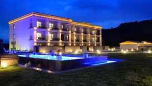 Un hotel de varios pisos con piscina e iluminación exterior.