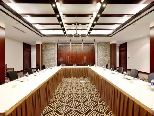 A conference room with a long table, chairs, and a patterned carpet.