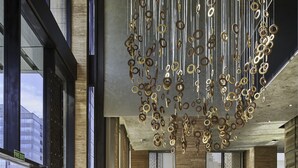Eine geräumige Lobby mit einem modernen Kronleuchter, großen Fenstern und einem Empfangstresen.