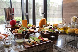 A buffet with various cheeses, fruits, and beverages. - The Den Bengaluru (Bengaluru)