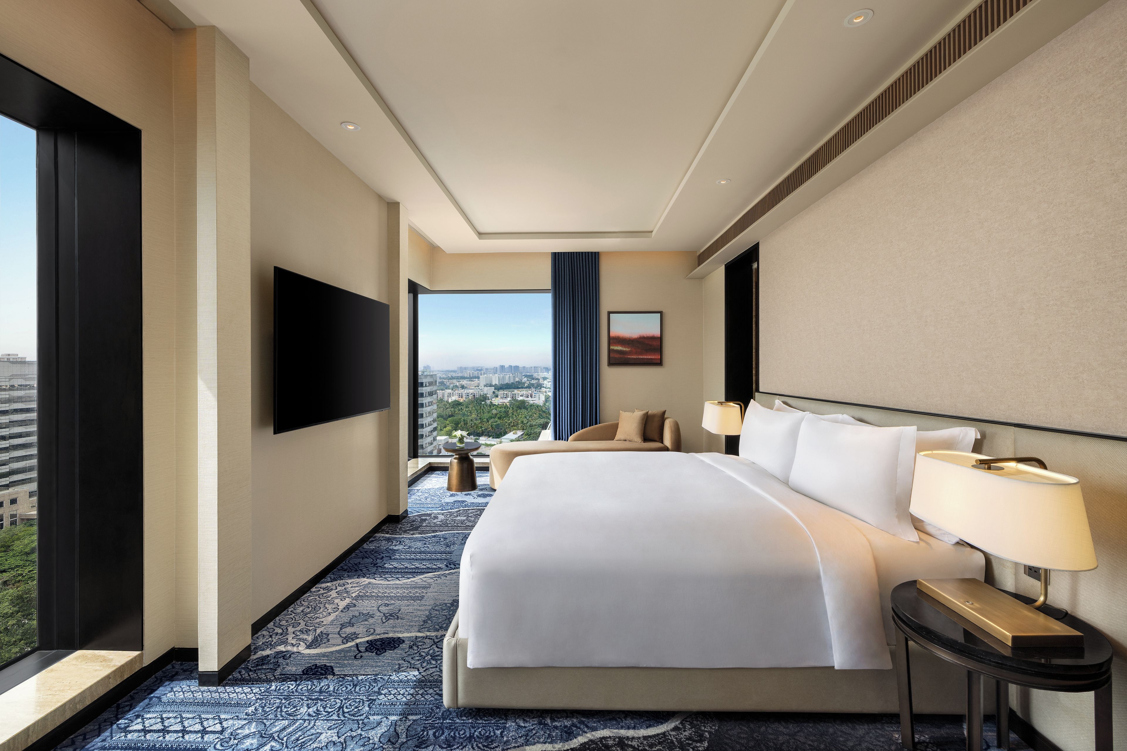 Habitación de hotel con una cama grande, televisión de pantalla plana, vista a la ciudad y diseño moderno.
